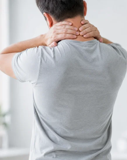 man med nackproblem som håller händer om nacken